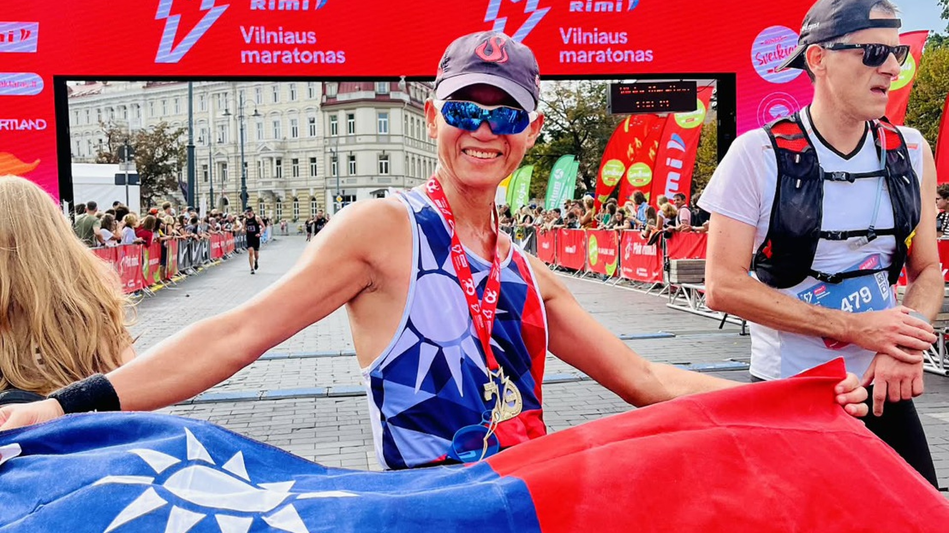 蔡國圳跑者在國際賽事身穿台灣國旗圖樣背心、手拿台灣國旗