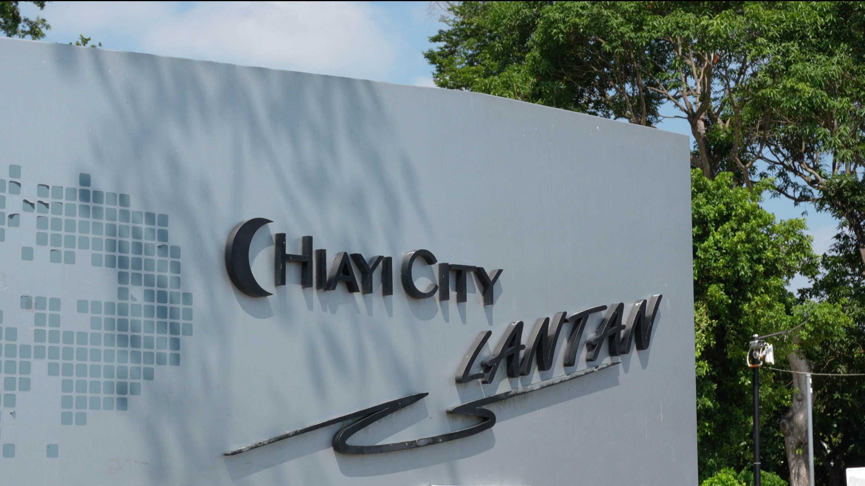 一面戶外的灰色地標牆，上面鑲嵌著「CHIAYI CITY LANTAN」