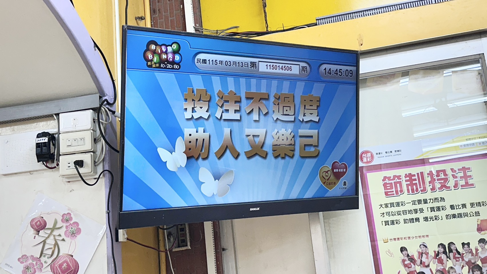 這是一張彩券行內的螢幕畫面，顯示「投注不過度，助人又樂己」的宣傳標語，提醒民眾在參與賓果賓果等博弈活動時應量力而為。