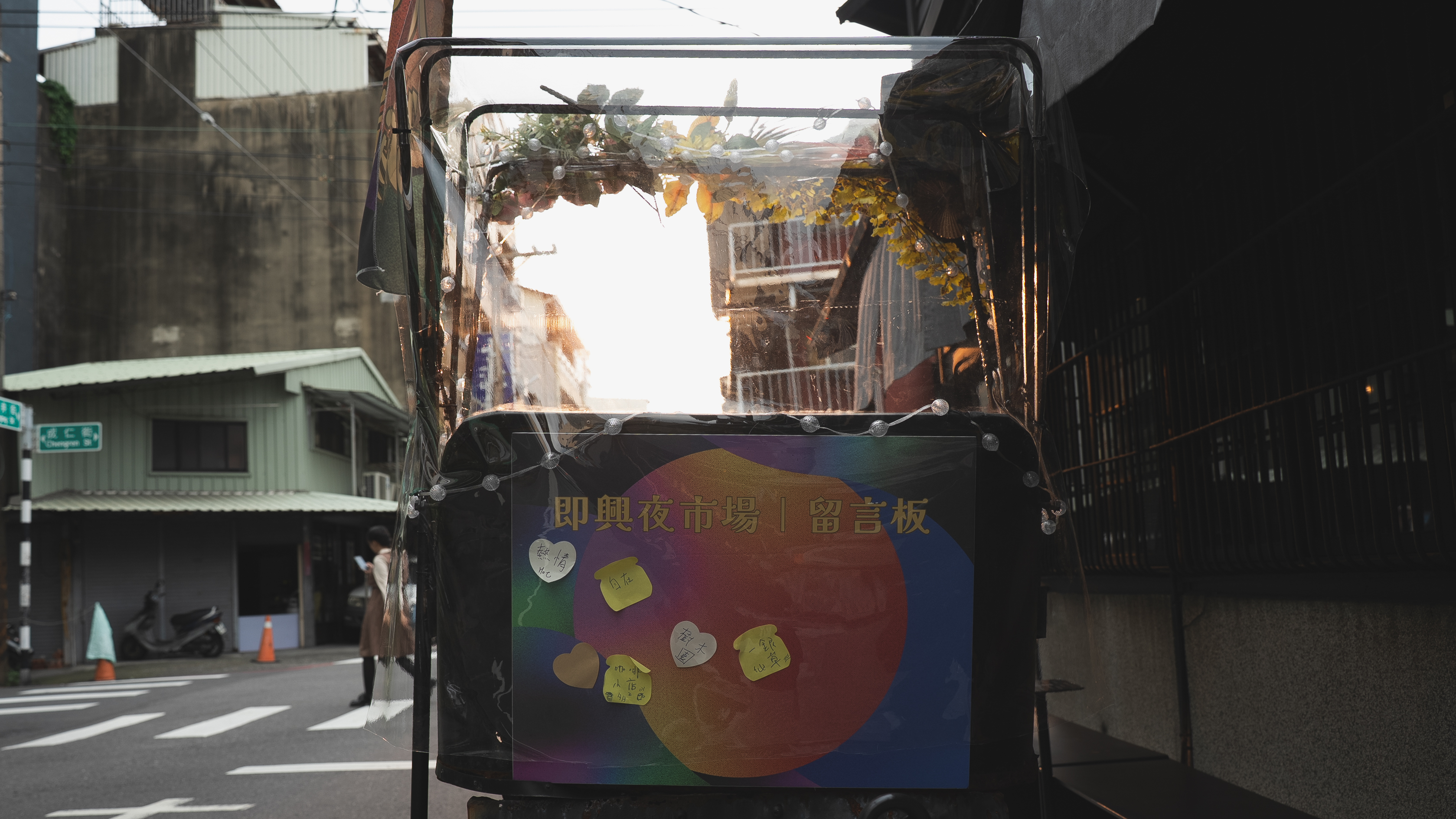 三輪車的後方掛著一塊「即興夜市場留言板」