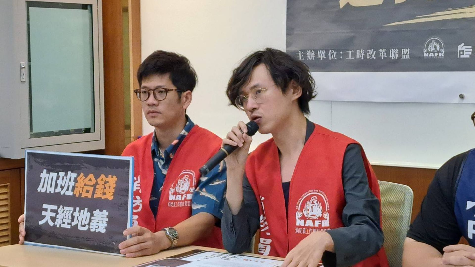 消防員工作權益促進會召開記者會，手持「加班給錢，天經地義」標語爭取合理的工時與補償。
