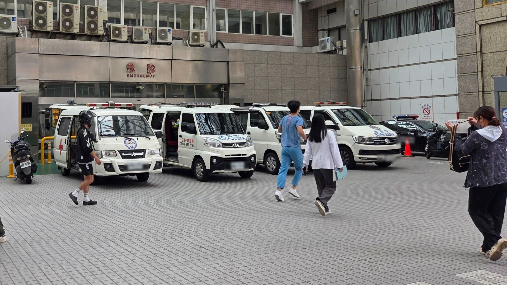 一家醫院的急診室入口外停放著多輛救護車，現場有醫護人員與民眾正在走動。