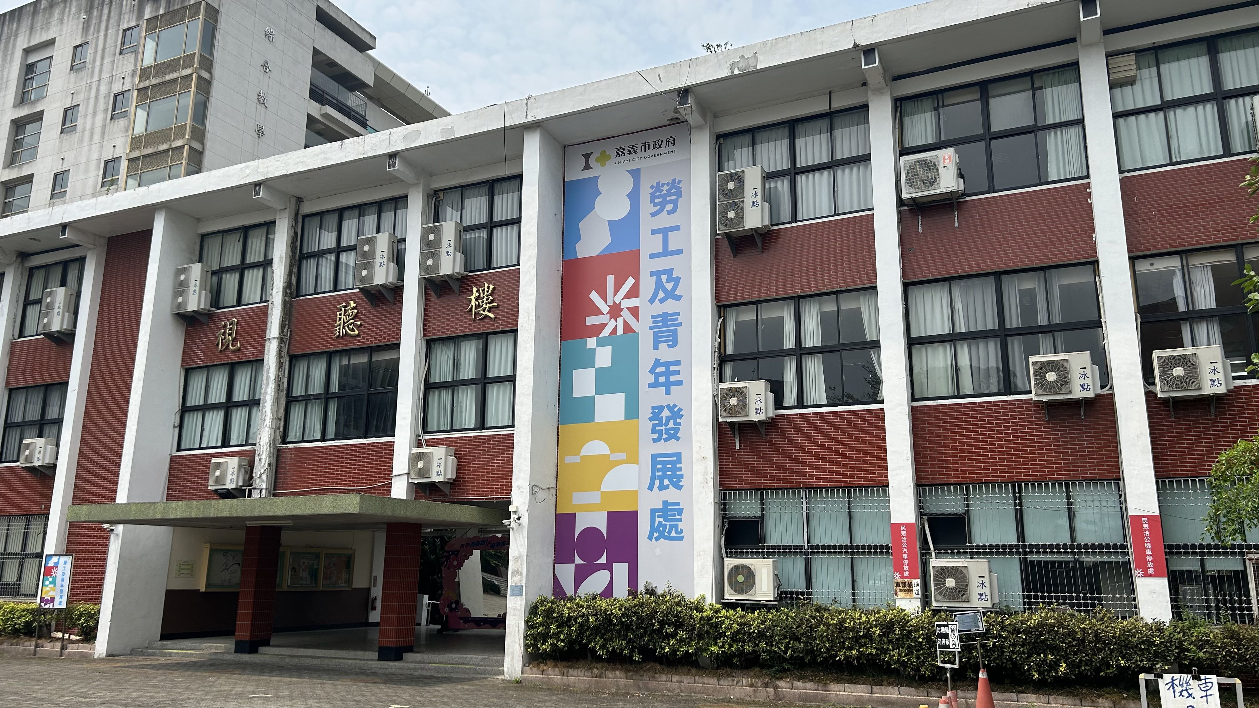 嘉義市政府「勞工及青年發展處」視聽樓建築外觀，牆面上掛有色彩繽紛的處室名稱看板。