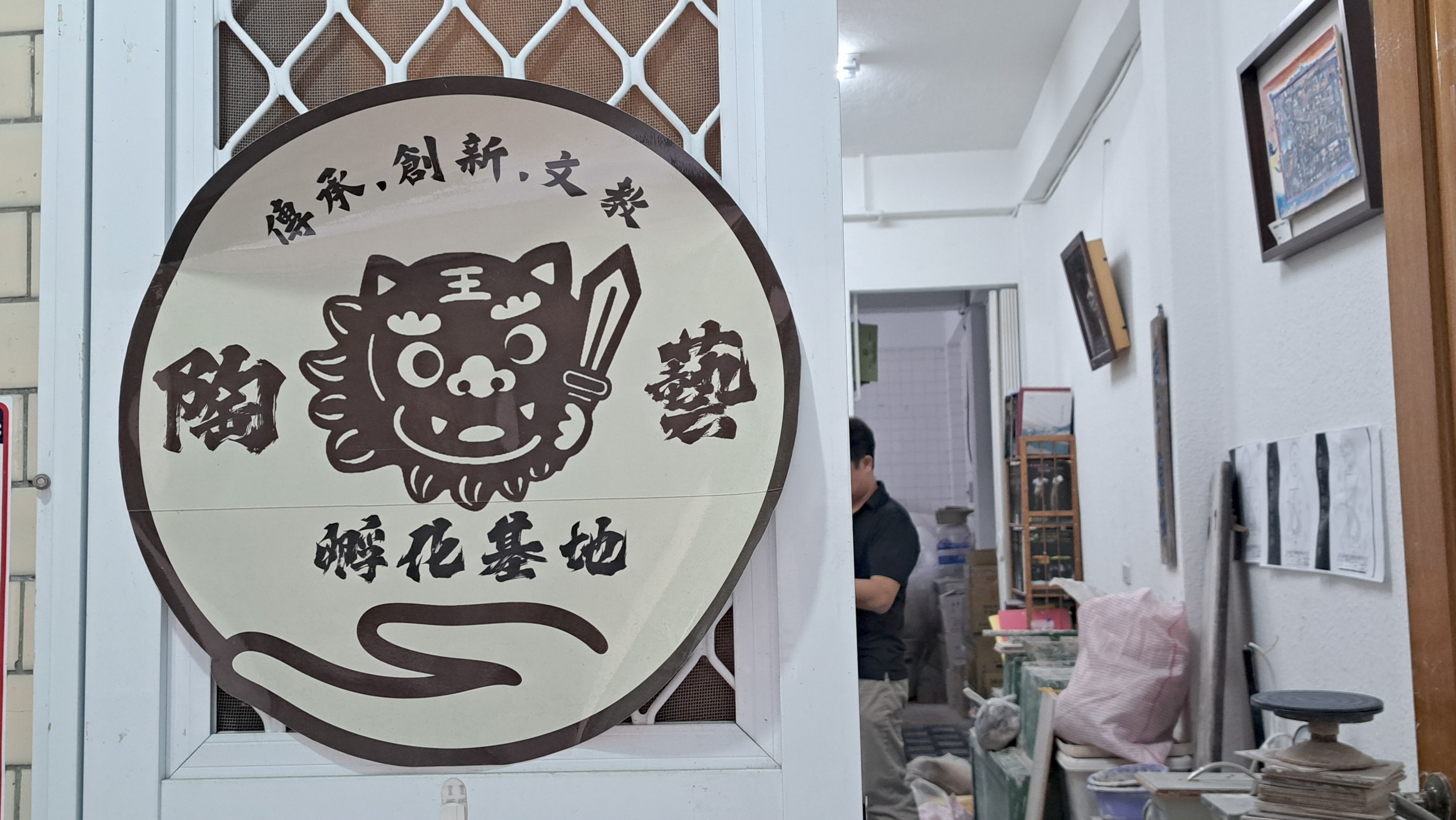 工作室的圓形標誌,上面畫著一隻手持寶劍的可愛劍獅插圖,並寫有「陶藝孵化基地」以及「傳承、創新、文教」的字樣。