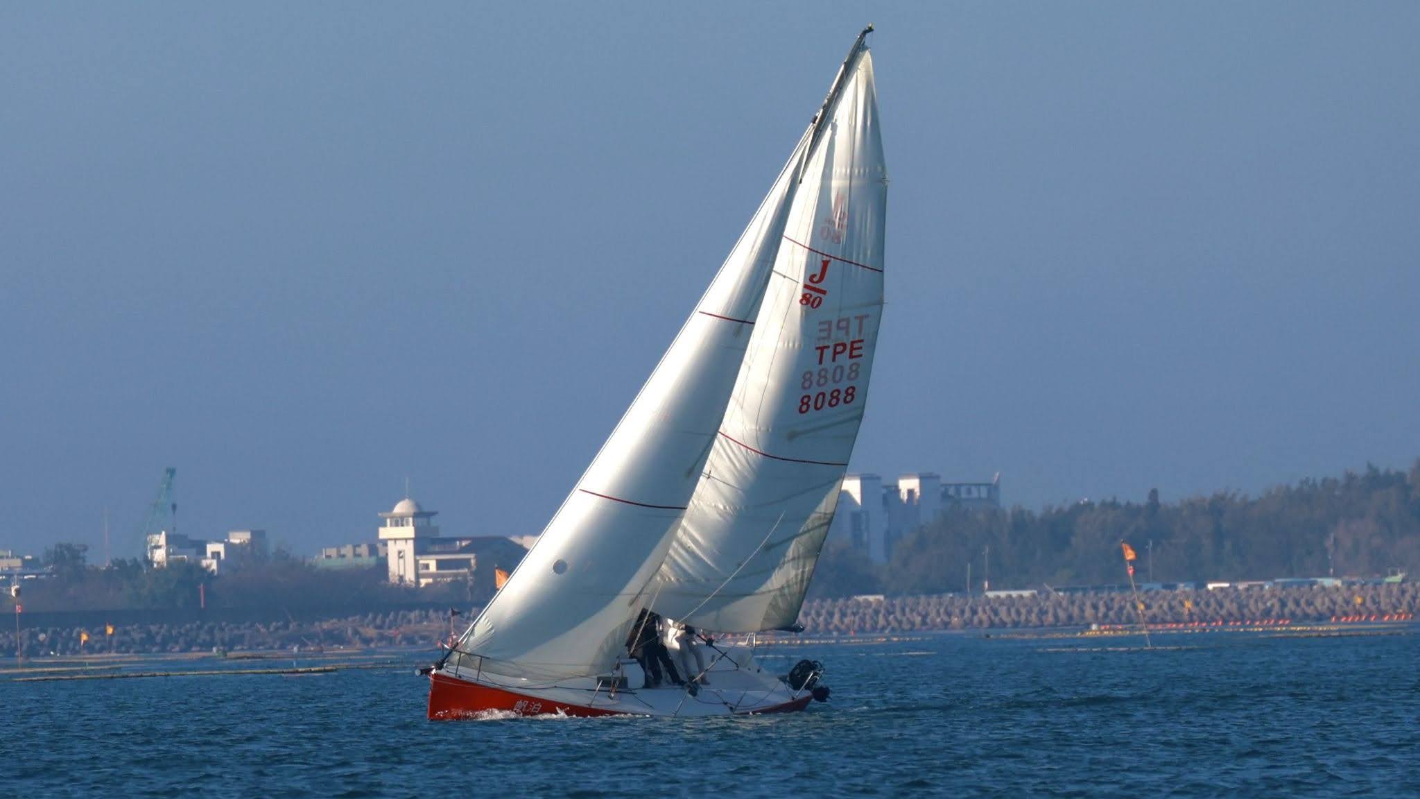  紅色帆船在海面上壓舷航行。