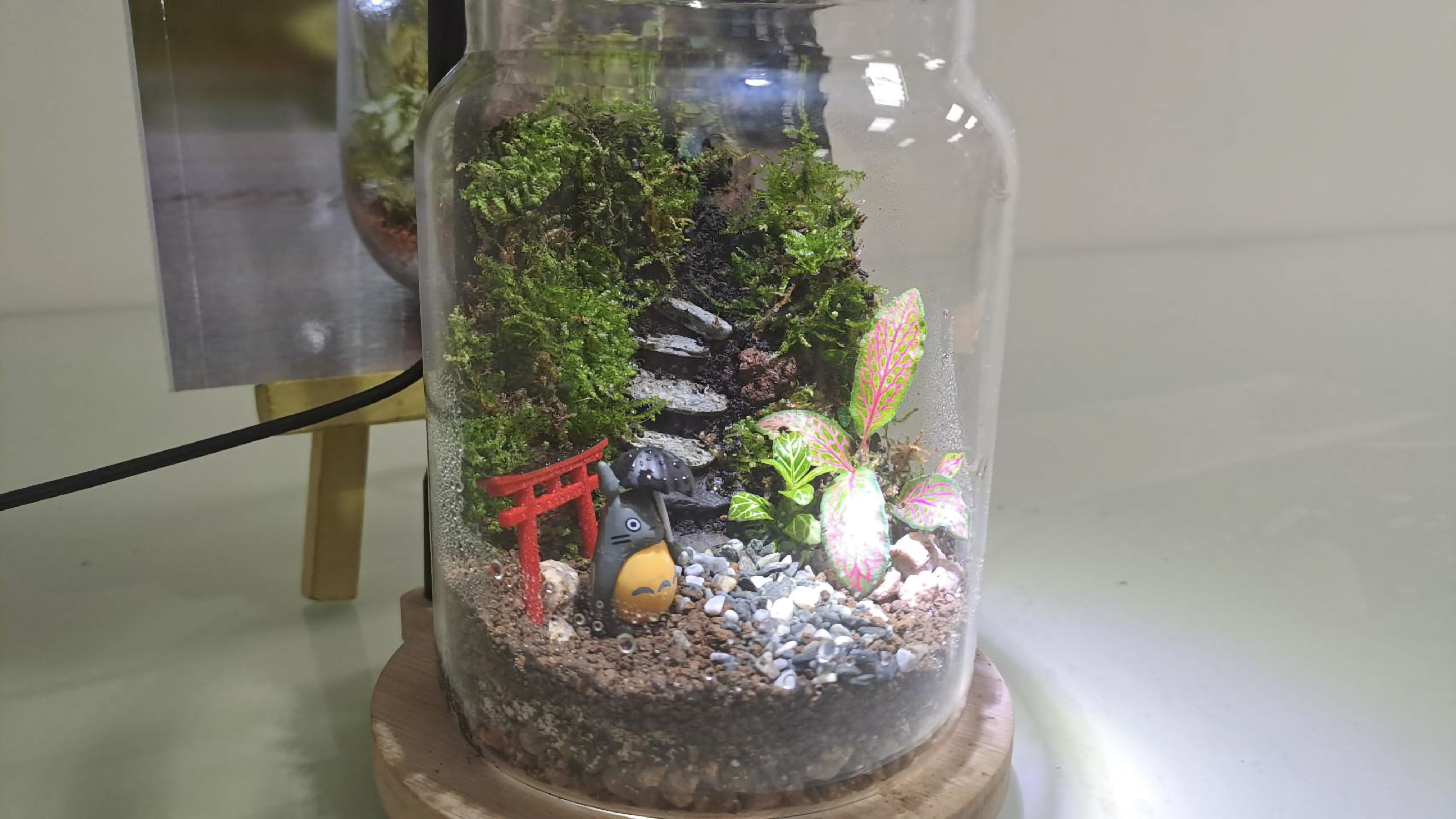 生態瓶成品外觀，瓶中的階梯前放有龍貓與日本鳥居的小型公仔裝飾