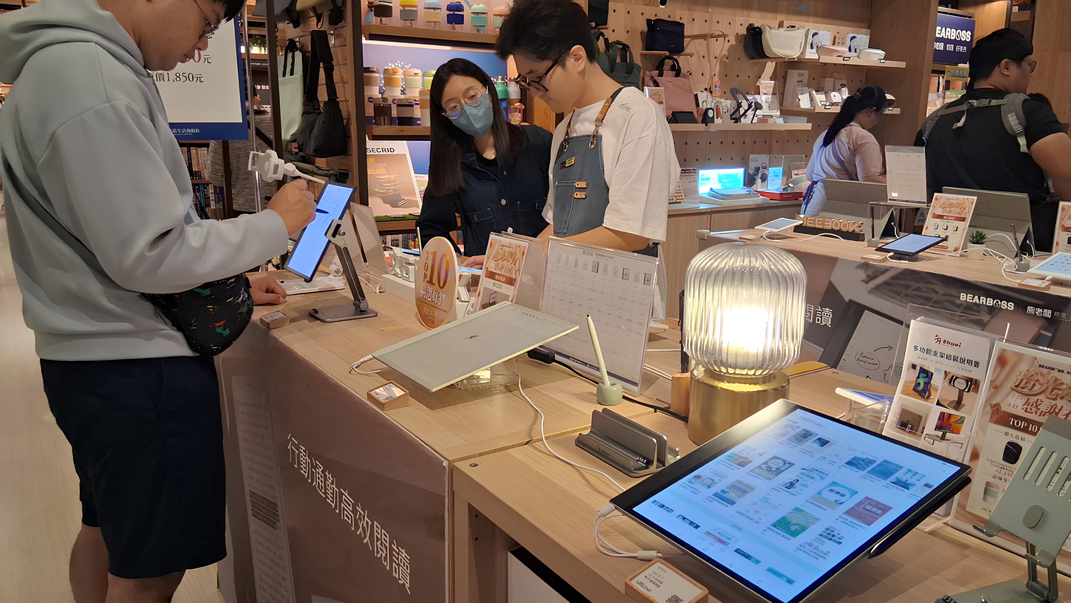 電子書閱讀器專賣店的現場照,店員正為顧客介紹產品。