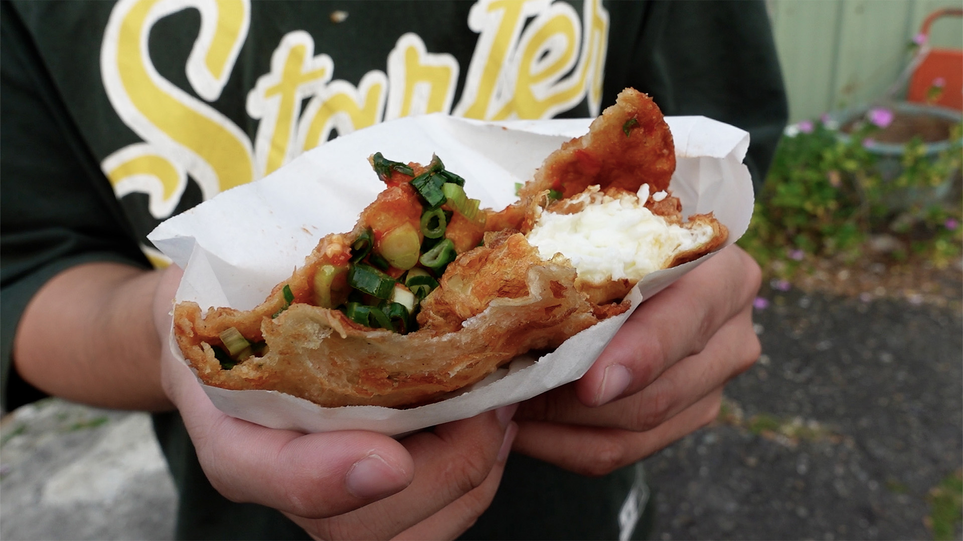 一雙手拿著炸蛋蔥油餅