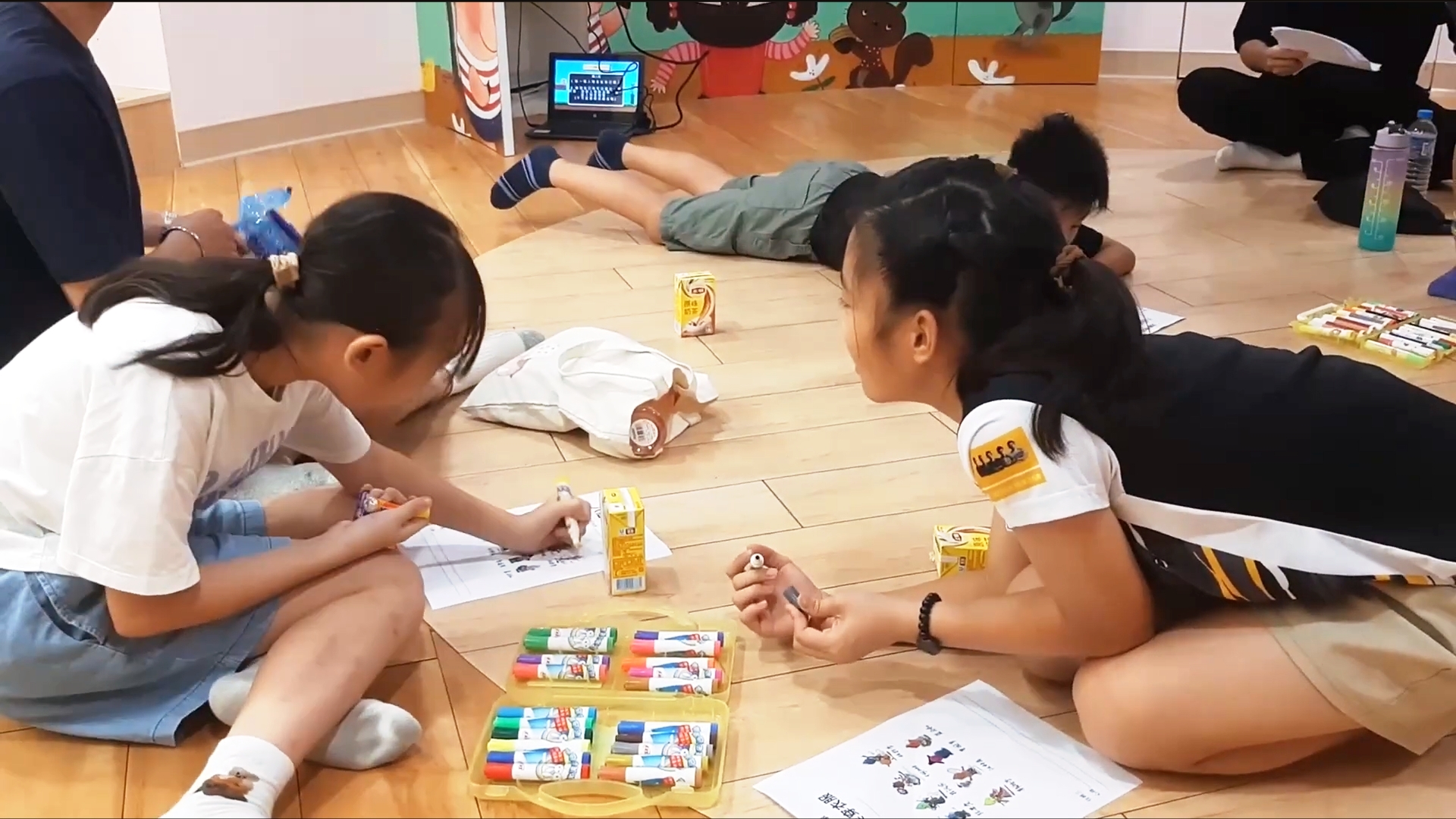 孩子們在地上拿著彩色筆在紙張上作畫