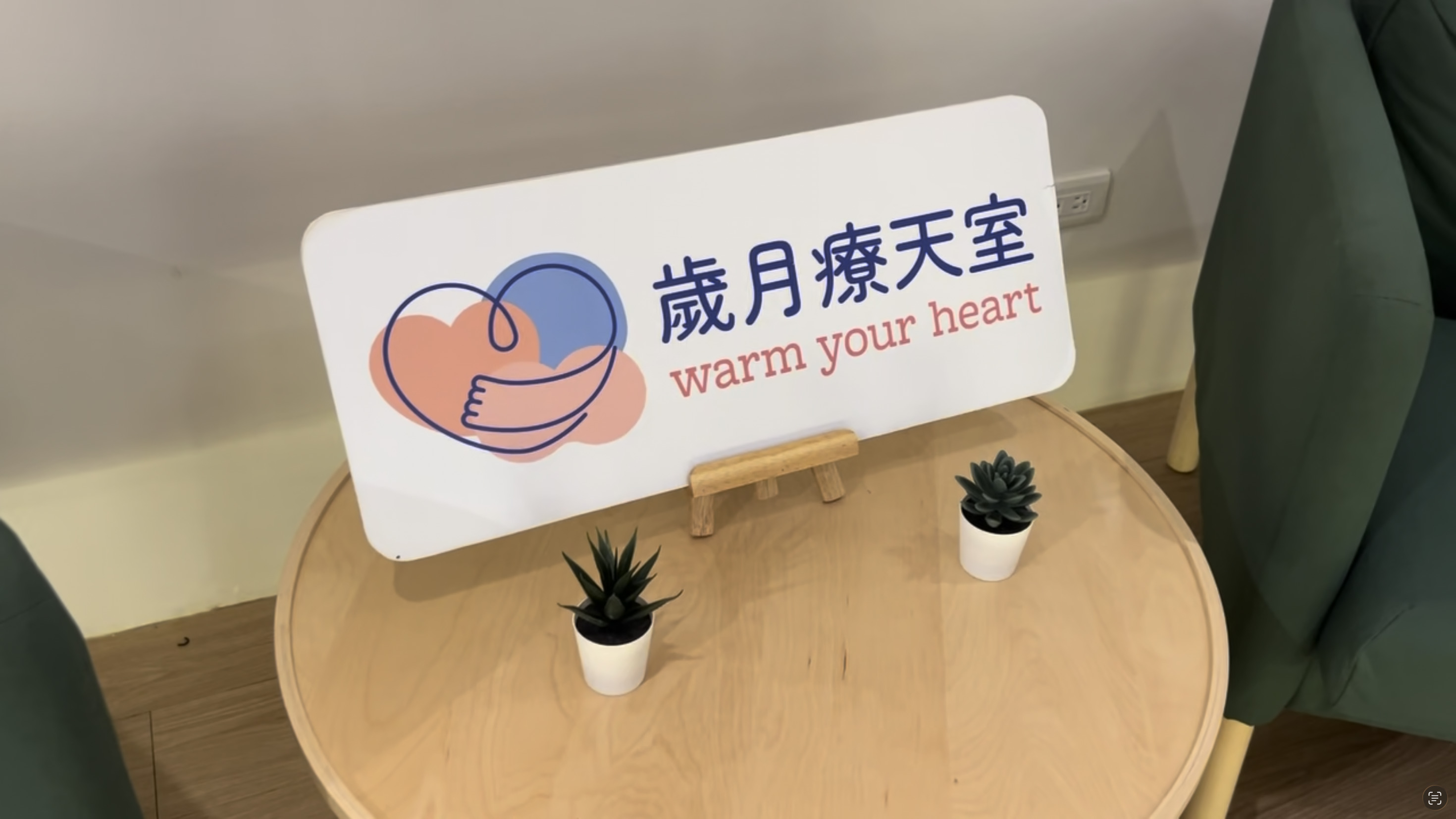 圓形木桌上放置著「歲月療天室」的品牌牌卡。