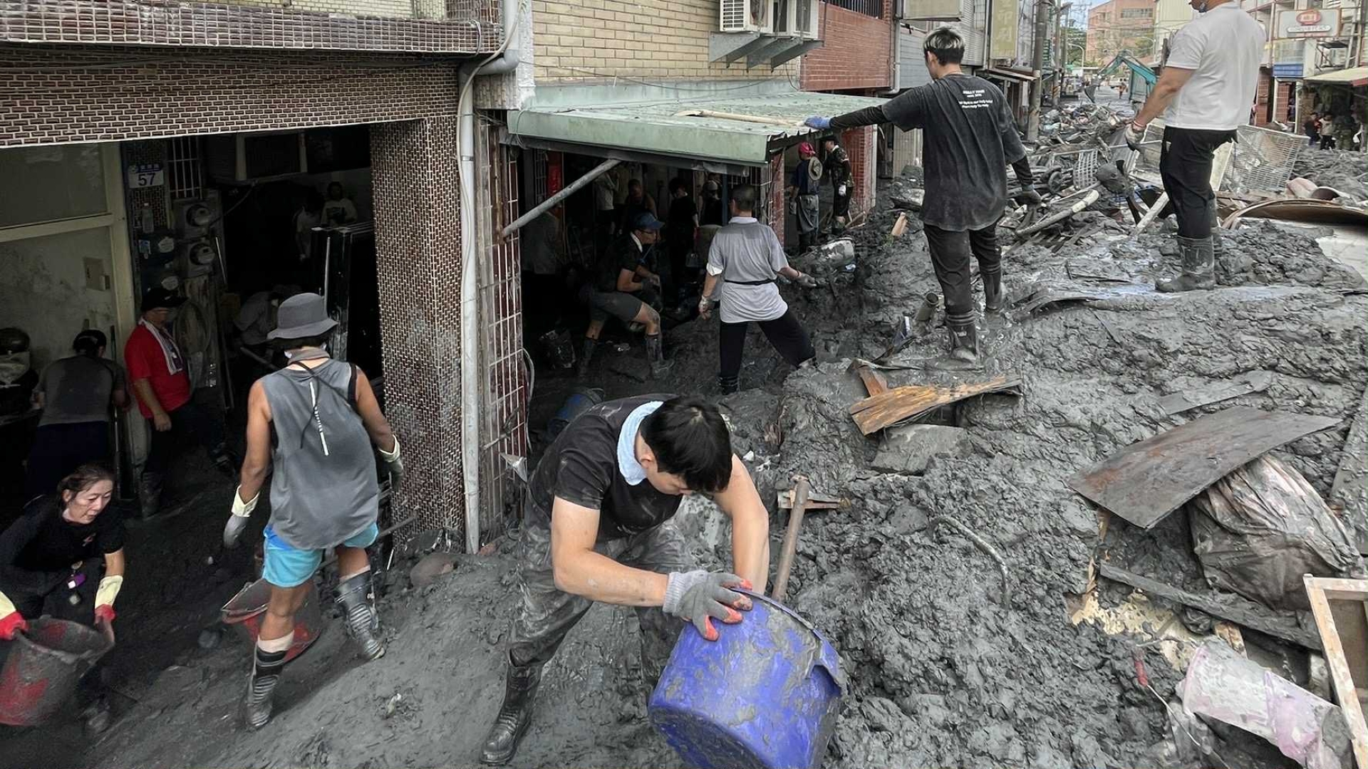 泥土堆積將近一層樓高，志工忙於清理。