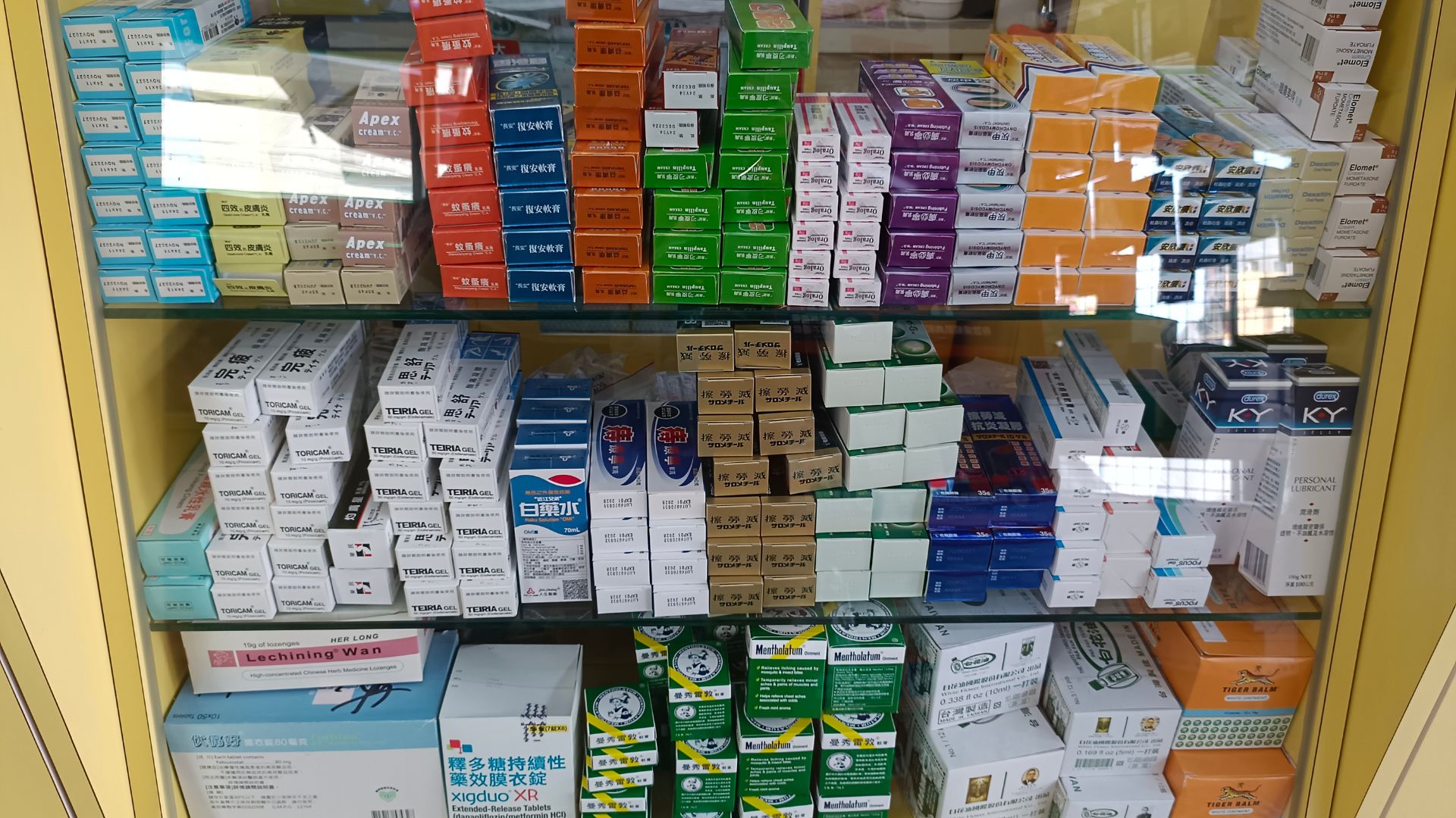 藥局玻璃展示櫃內整齊排列著各式各樣的盒裝藥品、藥膏與醫療用品。