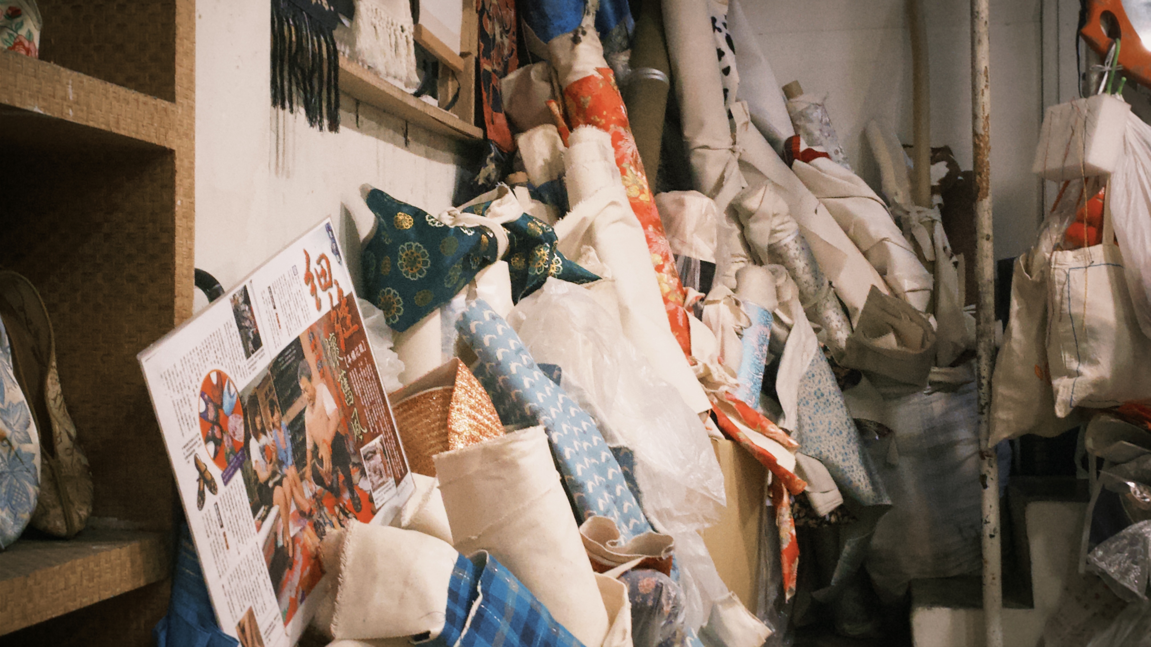 牆角堆放著大量參差不齊、捲成軸狀的布料