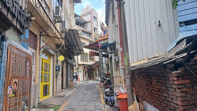 一條具有台灣傳統風貌的狹窄石板巷弄，兩側建築呈現新舊交融的景象。