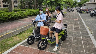 學生們騎乘電動自行車在校園內的路邊聊天