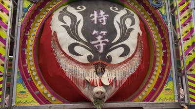 一頭背部畫有圖騰與「特等」字樣且裝飾華麗的巨大神豬供品，被安置在色彩鮮豔的祭祀展示架上。