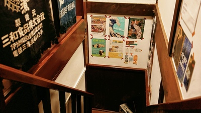 樓梯的走廊上張貼著小小文化創意有限公司在日本進行藝文活動的相關畫報