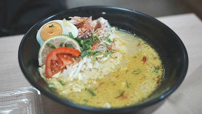 經典印尼雞湯「Soto Ayam」外觀,黃色的雞湯裡有番茄、雞蛋和蔬菜等配料