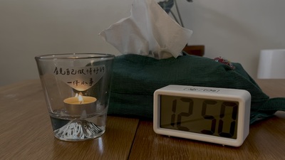 有一盞點燃的小蠟燭，燭台杯身上貼著一張手寫貼紙，上面寫著：「看見自己做得好的一件小事」。